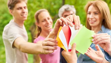 Group holding colorful papers outside.