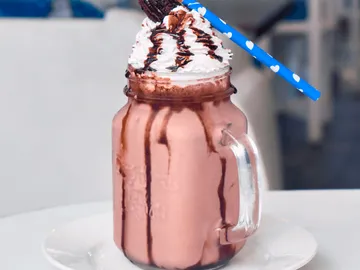 Ein Glas Milchshake mit Sahne und Schokoladensauce.