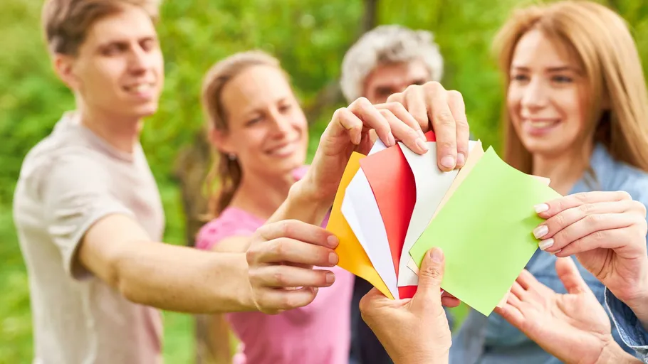 Gruppe hält buntes Papier im Freien.