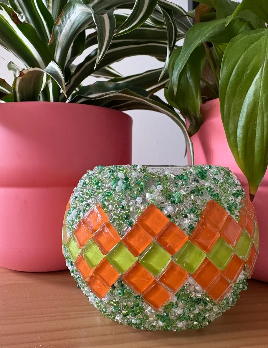 Mosaikglasvase mit Pflanzen auf Holztisch.