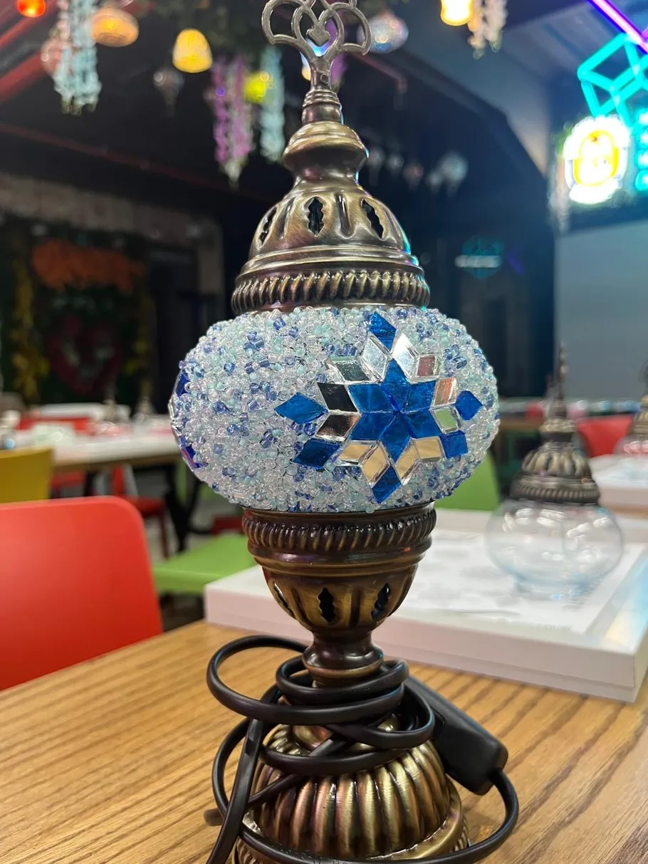 Dekorative Mosaiklampe auf Holztisch drinnen.