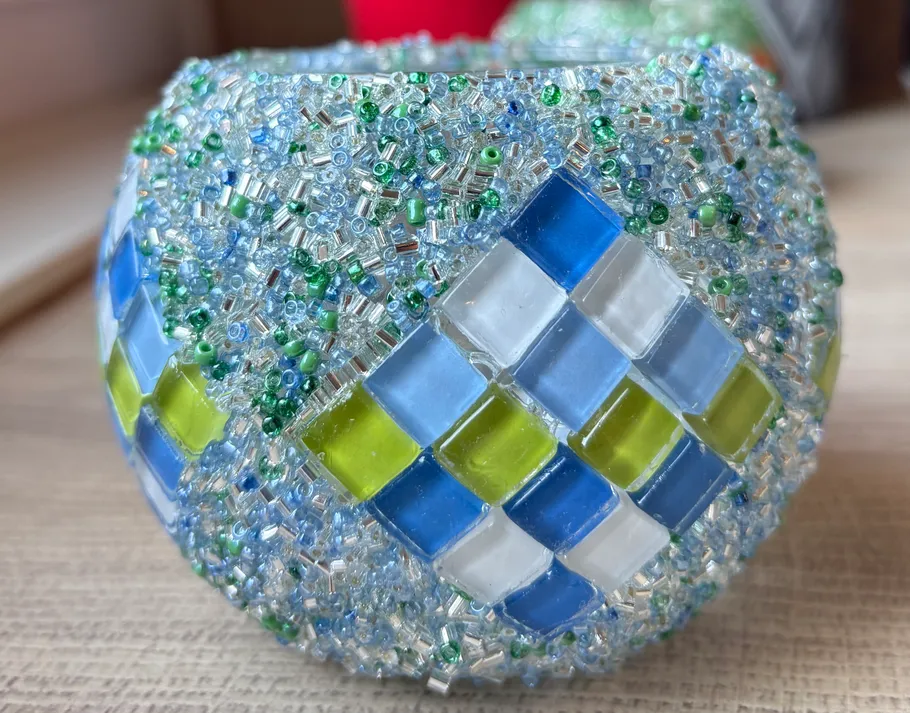 Bunter Mosaik-Kerzenhalter auf einem Tisch.