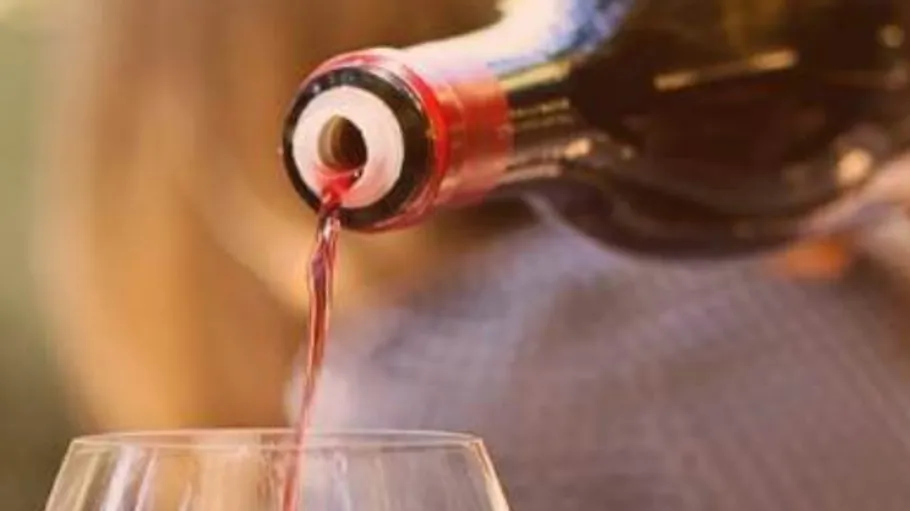 Weinflasche schenkt Rotwein in Glas ein.