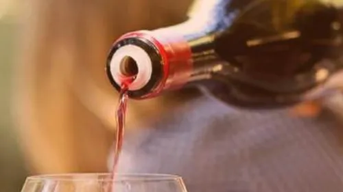 Wein wird aus Flasche ins Glas gegossen, unscharfer Hintergrund.