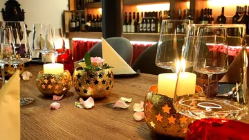 Candlelit table with wine glasses and petals.