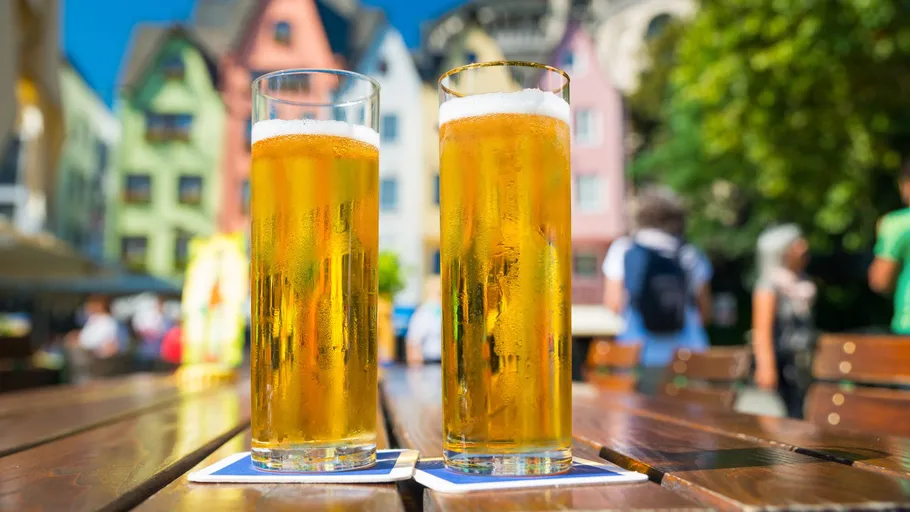 Two beers on a table in outdoor setting.