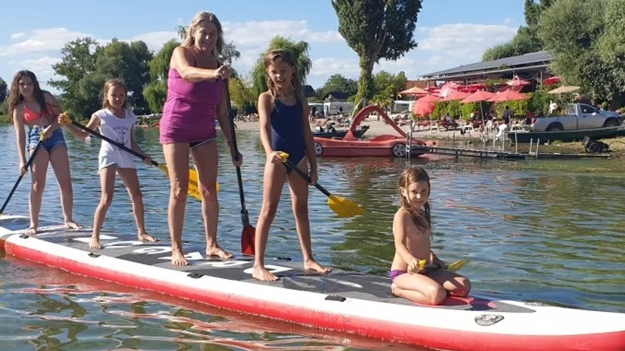 Gruppe paddelt auf einem See nahe einem Café.