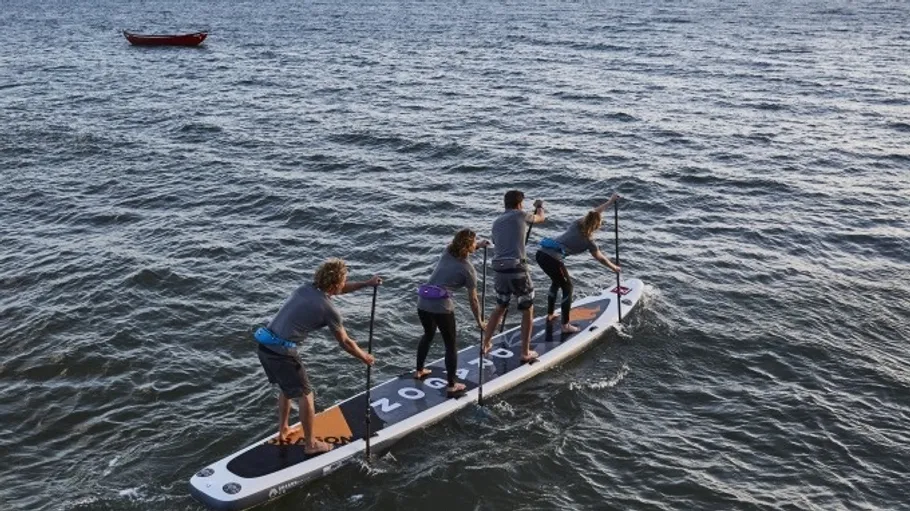 Vier Personen paddeln auf offenem Wasser.
