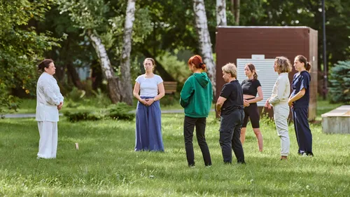 Group practicing meditation outdoors on grass.