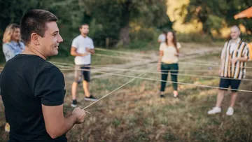 People in a circle holding strings outdoors.