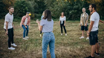 People in a circle playing catch outdoors.