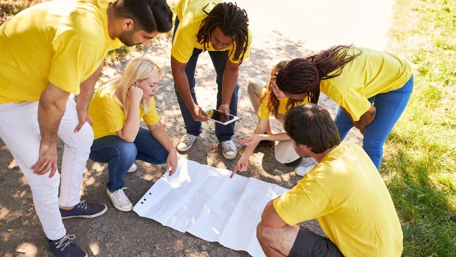 Group studying map outdoors wearing yellow shirts.