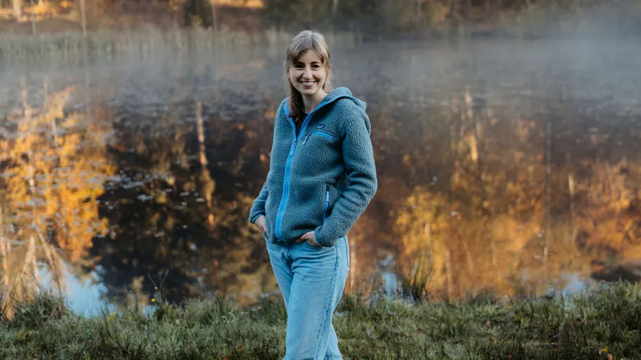 Frau steht an nebligem See im Herbst.