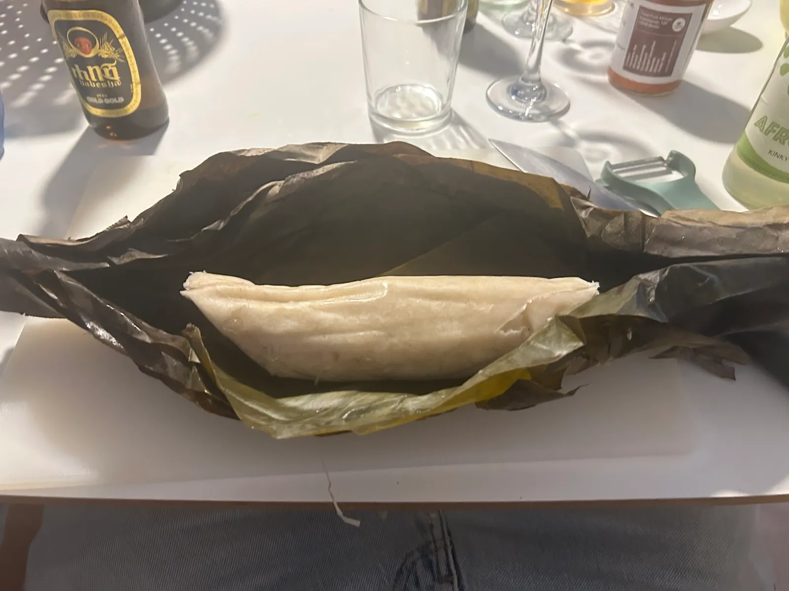 Tamale wrapped in banana leaf on a table.