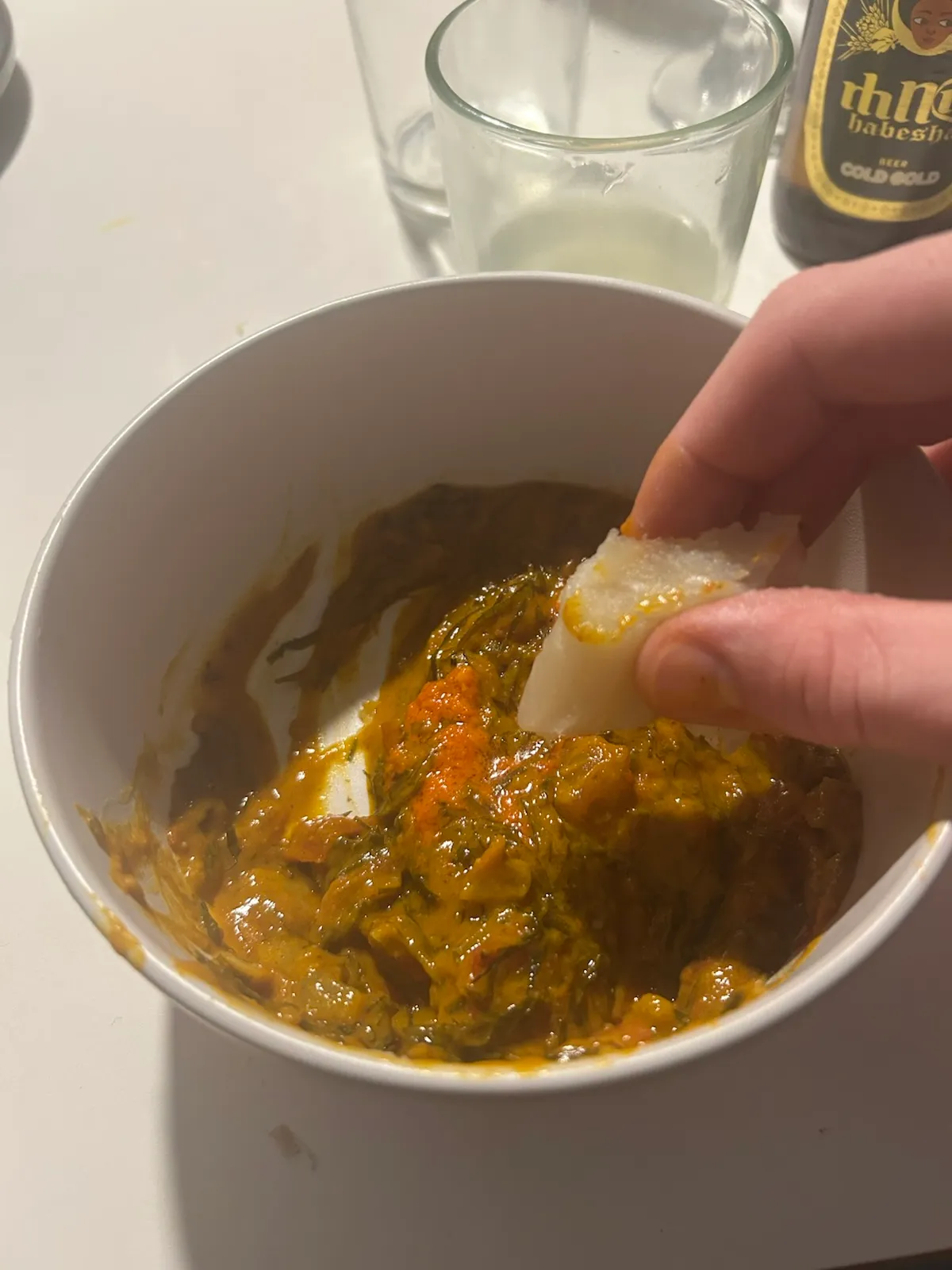 Hand dipping bread into stew bowl.