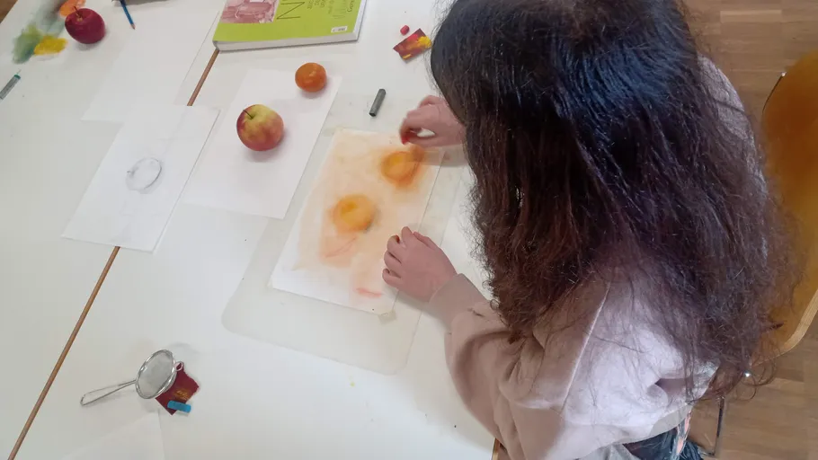 Person drawing fruit at the table.
