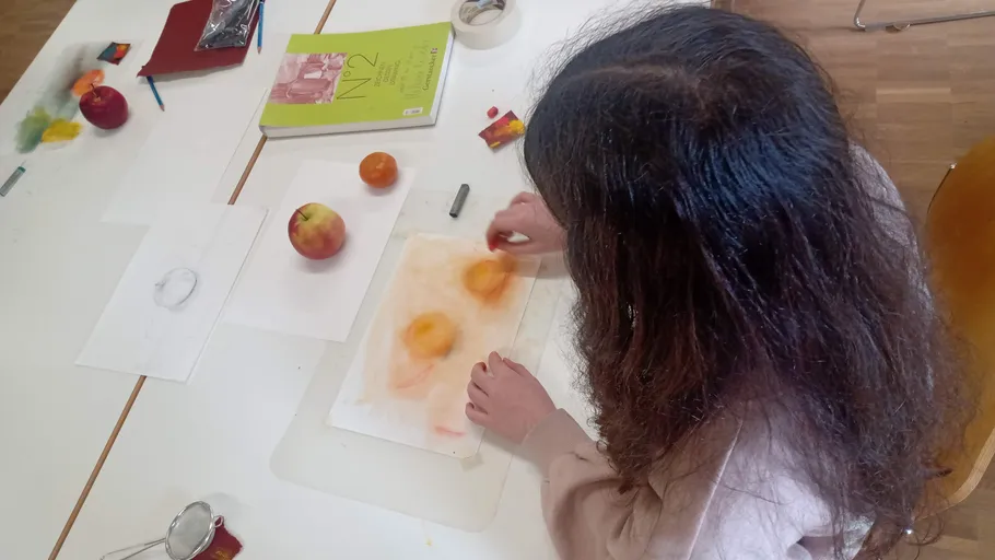 Person drawing fruit at the table.