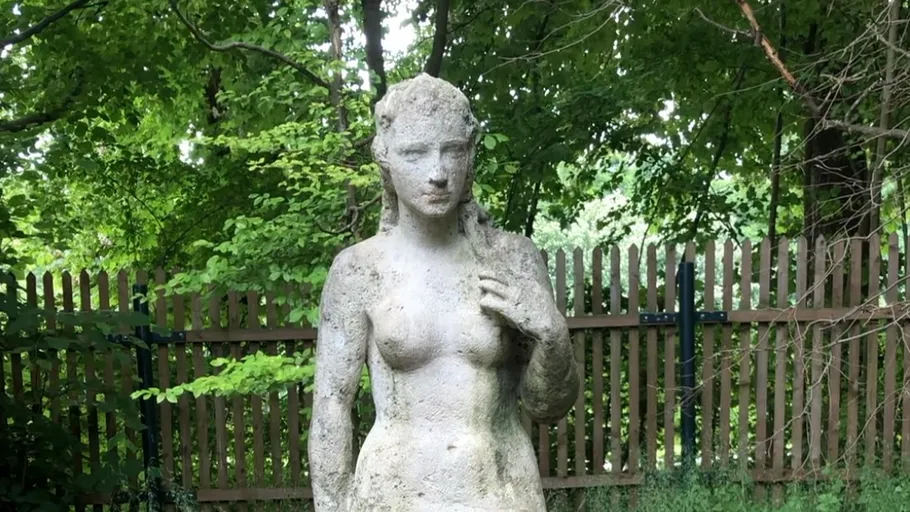 Steinskulptur einer Frau im Garten.