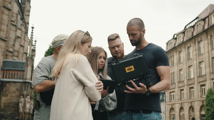 Group examining equipment outside historic building.