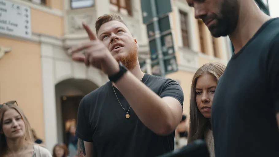 Man pointing while talking to group outside.