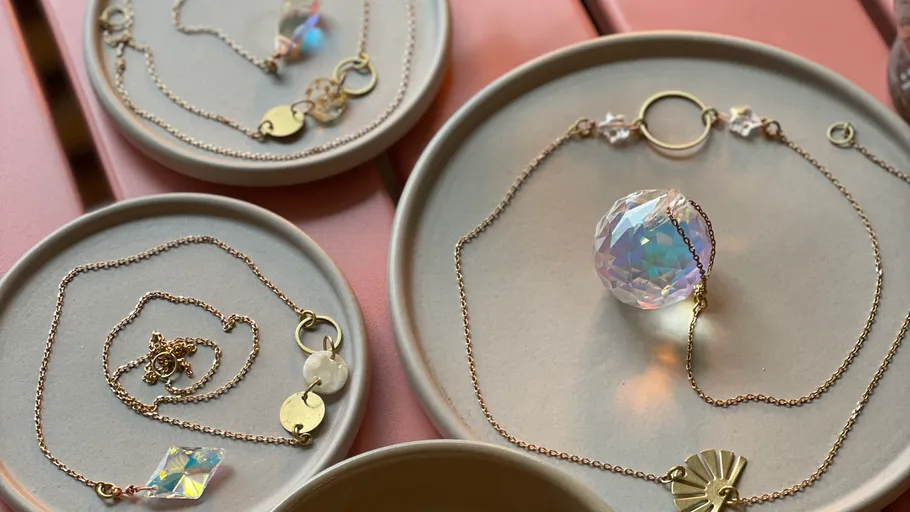 Schmuck auf Tellern auf rosa Tisch gezeigt.