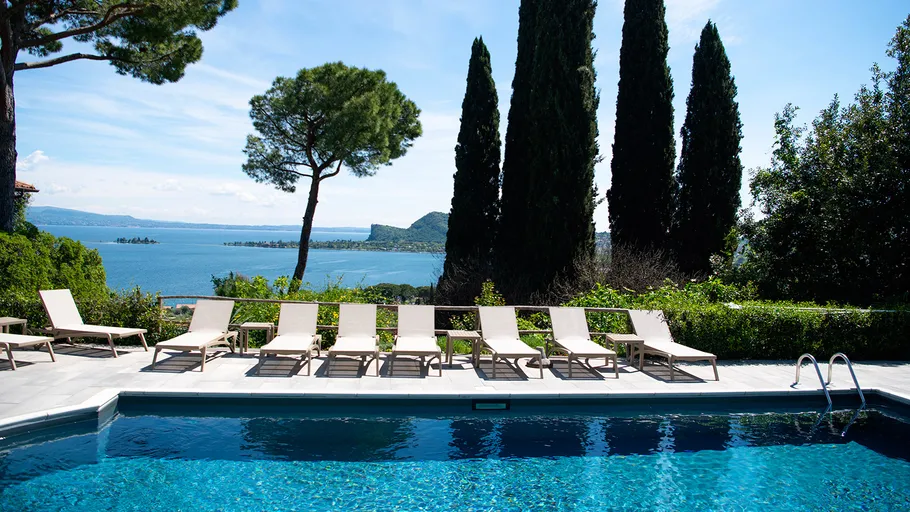 Pool with loungers overlooking a lake view.