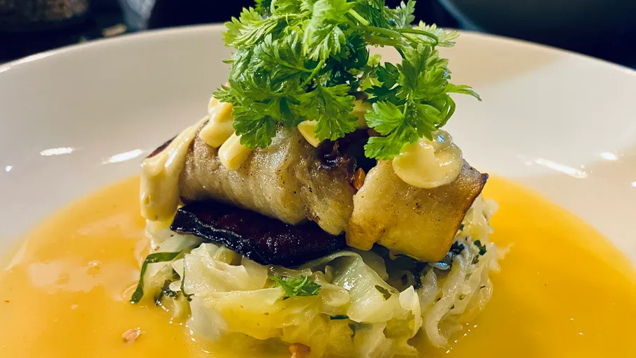 Rolled dish with herbs on a plate.