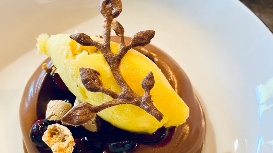 Schokoladendessert mit gelbem Sorbet und Garnitur.