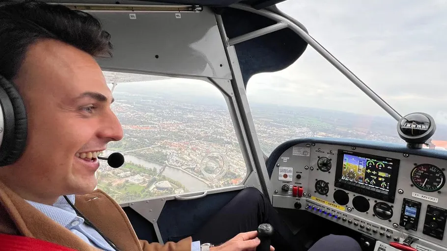 Pilot lächelnd, fliegt kleines Flugzeug, Stadt unten.