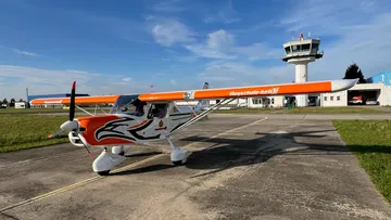Small white-orange plane on airport tarmac.