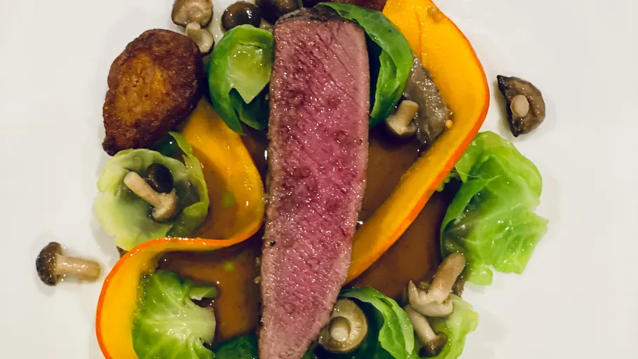 Sliced steak with vegetables on a plate.