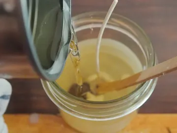 Wachskerzenwachs wird in ein Glas gegossen.