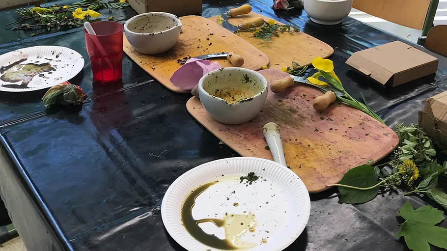 Unordentlicher Tisch mit Tellern, Schalen und Kräutern.