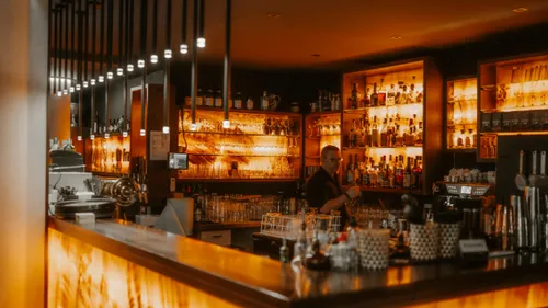 Bartender prepares drinks in a dimly lit bar.