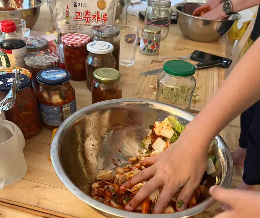 Hände mischen Kimchi-Zutaten in einer Schüssel.