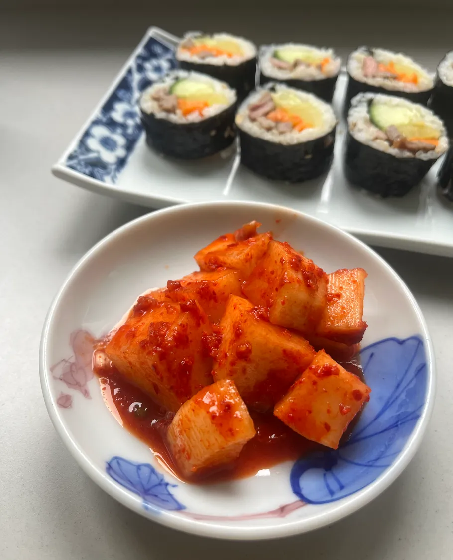 Rettich-Kimchi und Kimbap auf einem Teller.