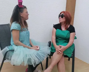 Two women sitting, talking indoors.