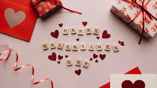 Scrabble-Steine buchstabieren 'Happy Valentine's Day', umgeben von Herzen.