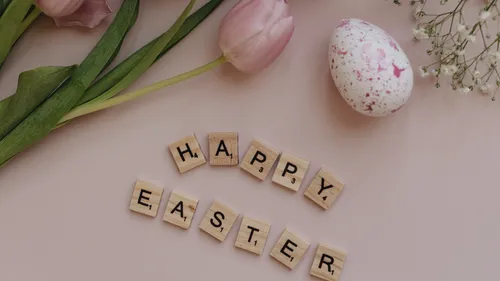 Holzbuchstaben buchstabieren 'Happy Easter' mit Tulpen.