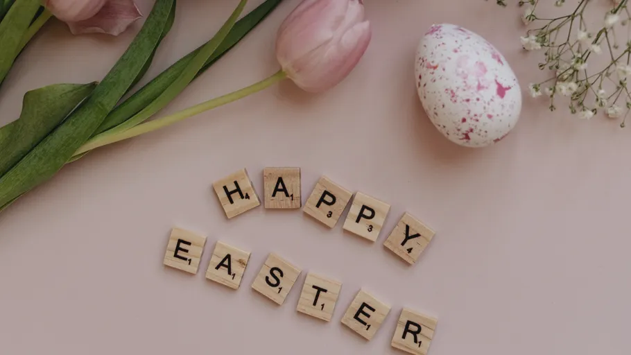 Holzbuchstaben buchstabieren 'Happy Easter' mit Tulpen.