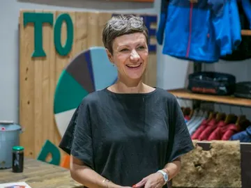Lächelnde Frau steht in einem Geschäft mit Kleidung.