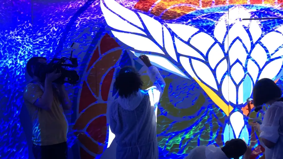 People painting on colorful backlit mural.