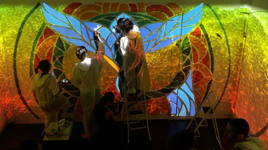 Artists painting colorful mural on wall.