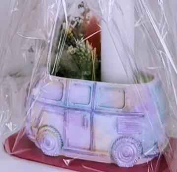 Colorful bus-shaped vase wrapped in plastic.