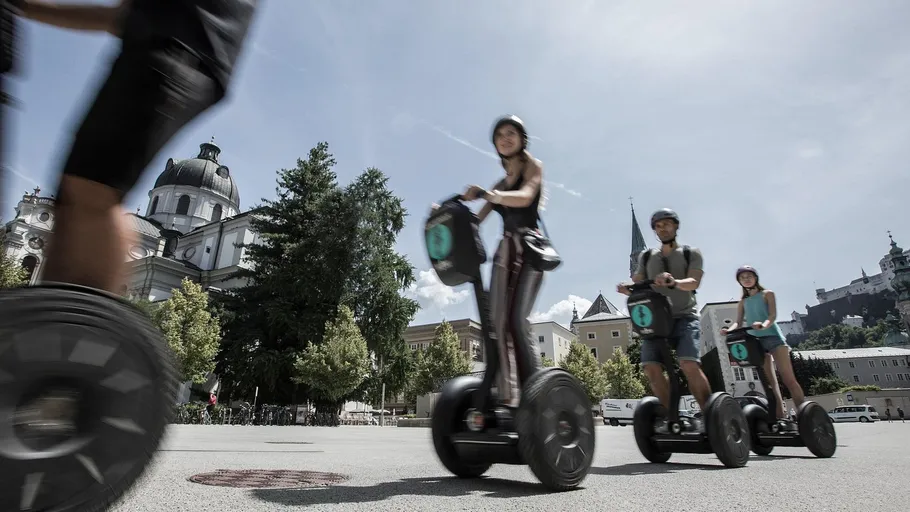 Menschen fahren Segways auf einem Stadtplatz.