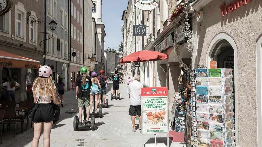 People ride Segways on a narrow street.
