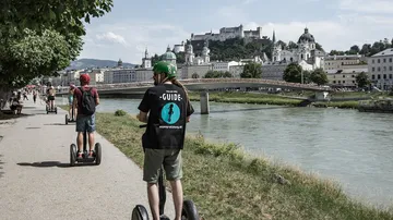 Personen auf Segways am Fluss, Stadtblick.