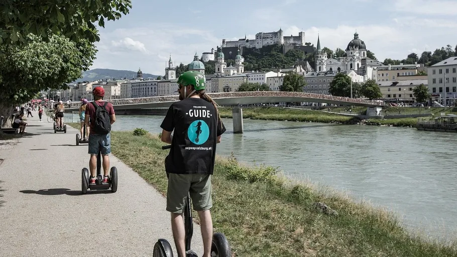 Personen auf Segways am Fluss, Stadtblick.