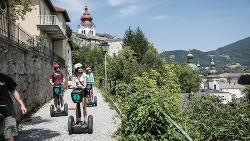 Menschen fahren Segways auf malerischem Kopfsteinpflasterweg.