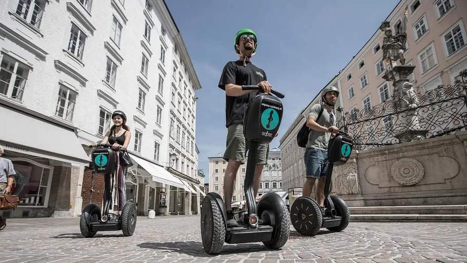 Leute fahren Segways auf einem Stadtplatz.